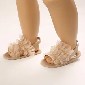 Vista detallada de sandalias beige para bebé con suela blanda y tul con volantes.