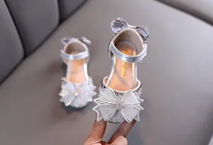 Détail de sandales de princesse argentées avec strass et nœud en tulle pour filles