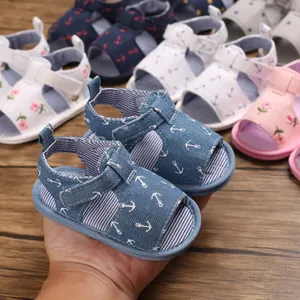 Détail de sandales pour bébé en denim bleu avec imprimé ancre sur fond de bois sombre