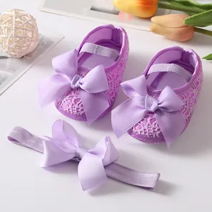 Close-up of cute purple lace baby princess shoes with large ribbon bows and matching headband