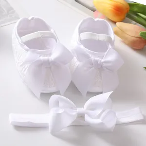 Detail view of white baby lace shoes and matching bow headband set for infants.