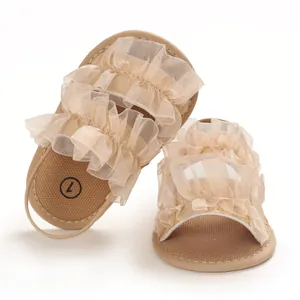 Detalle de sandalias de verano beige para bebé con suela blanda y malla con volantes