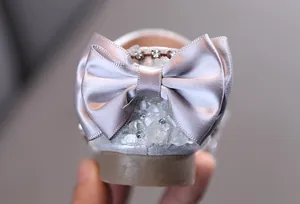 Détail de chaussures de princesse argentées avec nœud en satin et strass pour filles