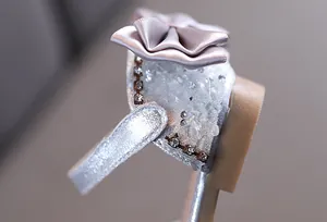 Détail du nœud en satin rose et des strass sur les sandales de princesse argentées