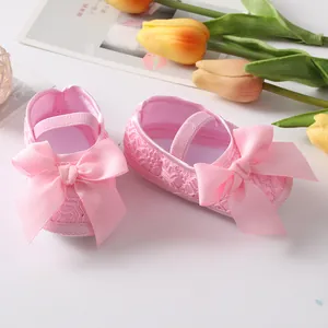 Detaillierte Nahaufnahme von rosa Baby-Prinzessinenschuhen mit Schleifen und Spitze.