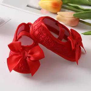Close-up detail of red lace baby princess shoes featuring a large elegant satin bow decoration