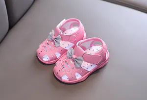 Nahaufnahme von rosa Kleinkindsandalen mit silberner Glitzerschleife und Strass
