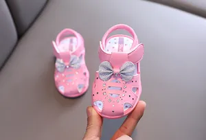Nahaufnahme der rosa Babysandalen für Mädchen mit Glitzerschleife und Strass.