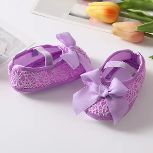 Close-up detail of cute purple lace baby princess shoes featuring a large decorative ribbon bow