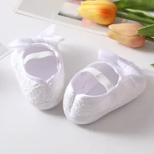 Close-up detail of white lace baby princess shoes with elegant ribbon bow for infants