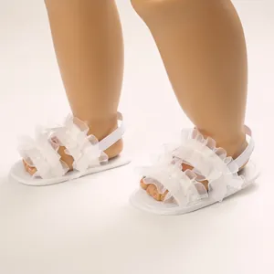 Detalle de sandalias blancas con volantes para bebé con suela blanda y correa elástica