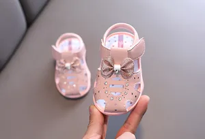 Nahaufnahme rosa Babysandalen für Mädchen mit glitzernder Schleife und Strass