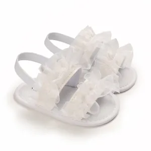 Detalle de sandalias de bebé con encaje blanco y correa elástica