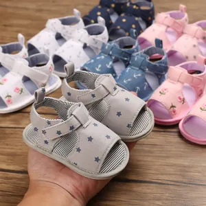 Détail de sandales d'été souples pour bébé avec motifs d'étoiles, fleurs et ancres.