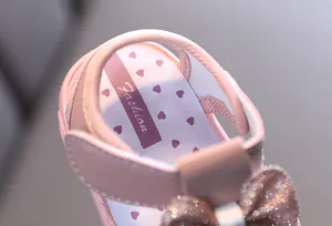 Detailaufnahme rosa Babysandalen mit Herzmuster und glitzernder Schleifenverzierung