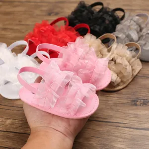 Detalle de sandalias rosas para bebé con suela blanda y volantes sobre madera