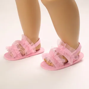 Primer plano de sandalias rosas para bebé con suela blanda y elegantes volantes de encaje