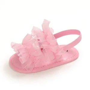 Primer plano de sandalias rosas para bebé con volantes y suela blanda