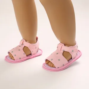 Gros plan sur les sandales roses pour bébé à semelle souple avec motif d'étoiles grises.