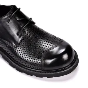 Nahaufnahme atmungsaktiver schwarzer Leder-Hohlraumschuhe mit Glanzkappe und dicker Gummisohle
