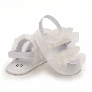 Detailed view of white baby sandals with delicate mesh ruffles and elastic straps