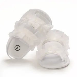 Close-up of white ruffled lace baby summer sandals with soft soles and elastic strap