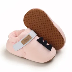 Vue détaillée de chaussures de marche pour bébé roses avec queue de dinosaure mignon