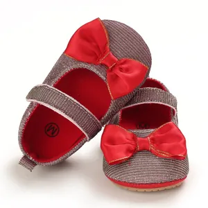 Detailansicht der Babyschuhe für Mädchen mit roter Schleife und Metallic-Stoff