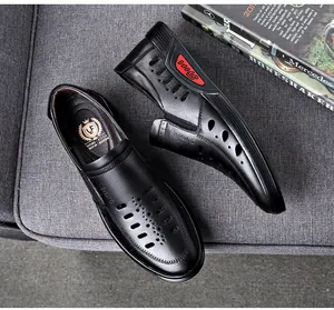 Detail view of black breathable hollow-out leather loafers for men on grey sofa.