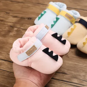 Gros plan de chaussures de marche roses pour bébés avec détail queue de dinosaure