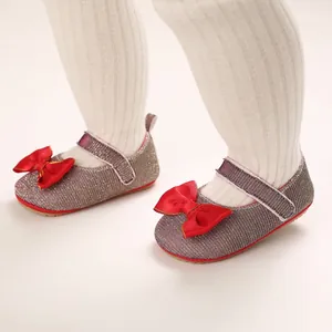 Detailansicht glitzernder silberner Babyschuhe mit roten Schleifen am Kleinkind