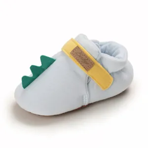 Gros plan sur une chaussure de bébé avec un décor de queue de dinosaure vert