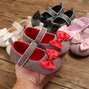 Nahaufnahme glitzernder Baby-Prinzessin-Schuhe mit roter Satinschleife und weicher Sohle