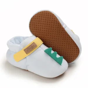 Détail de chaussures de marche bleues pour bébé avec queue de dinosaure et semelle antidérapante