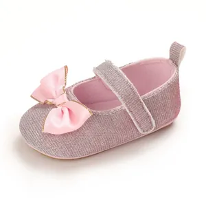 Detail view of pink glitter baby princess shoe featuring a satin bow and velcro strap