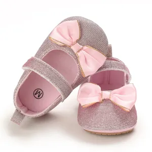Nahaufnahme von rosa glitzernden Babyschuhen mit Seidenschleife und Goldrand