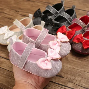 Detailansicht von glitzernden Baby-Lauflernschuhen für Mädchen mit rosa Satinschleifen