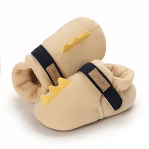 Détail rapproché de chaussures bébé beiges avec un joli design de queue de dinosaure jaune