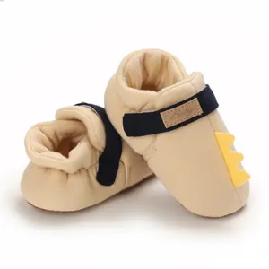 Vue détaillée de chaussures de marche jaunes pour bébé avec queue de dinosaure en 3D.