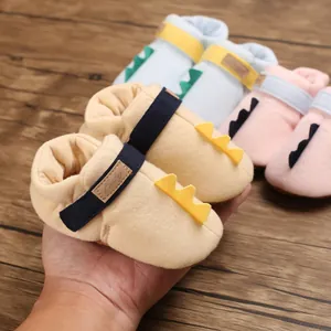 Gros plan de chaussures bébé dinosaure en tissu doux avec une ouverture élastique