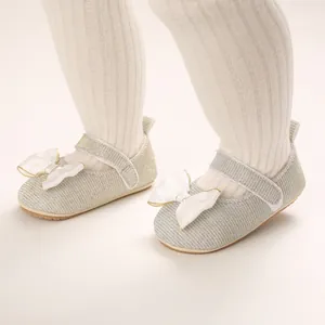 Nahaufnahme von Baby-Prinzessin-Schuhen in Silber mit weißer Satinschleife