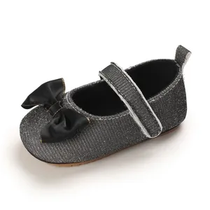 Detailansicht glitzernder grauer Baby-Prinzessinnenschuh mit Schleife und Klettverschluss.