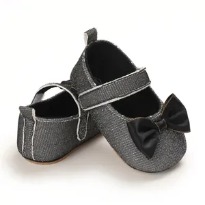 Detaillierte Nahaufnahme von glitzernden Baby-Mädchen-Schuhen mit schwarzer Satinschleife.