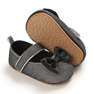 Detailansicht silberner Glitzer Baby Schuhe mit schwarzer Schleife und rutschfester Sohle.