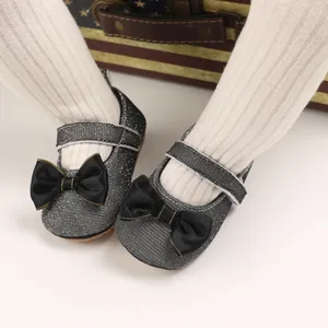 Nahaufnahme von silbernen Glitzer-Prinzessinenschuhen für Babys mit schwarzer Schleife