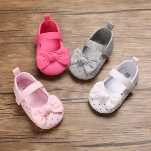 Soft sole baby princess walking shoes with polka dots and bow detail on wooden background