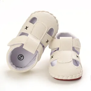 White infant soft-sole sandals with decorative cross patterns for toddler pre-walkers