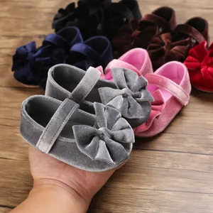 Detail of a soft grey velvet baby girl walking shoe with a large bow decoration feature