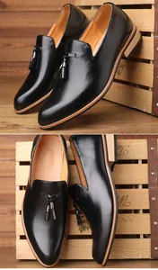Close-up detail of black leather loafers with tassels on a rustic wooden background