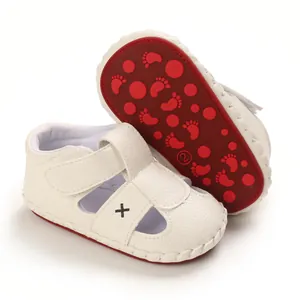 Detail view of white baby sandals featuring a non-slip red sole and soft leather.